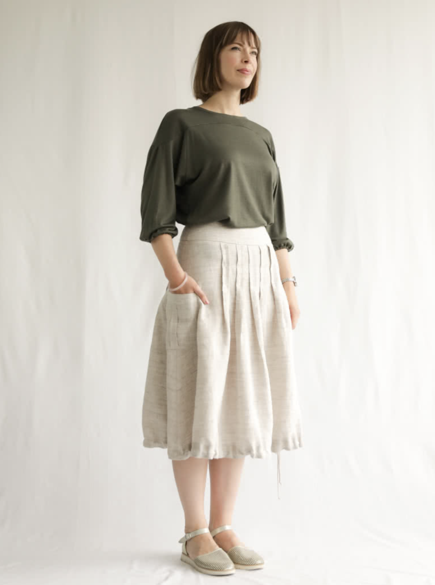 Woman wearing the Richmond Utility Skirt sewing pattern from Style Arc on The Fold Line. A skirt pattern made in washed linen, poplin or crepe fabrics, featuring front and back topstitched box pleats, pockets with centre box pleat, side seam invisible zip