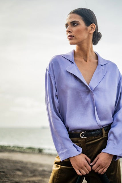 Woman wearing the Risa Blouse sewing pattern from Fibre Mood on The Fold Line. A wrap blouse pattern made in medium weight smooth flowing fabrics, featuring a deep V-neckline, collar, lapels, drop shoulders and straight sleeves.