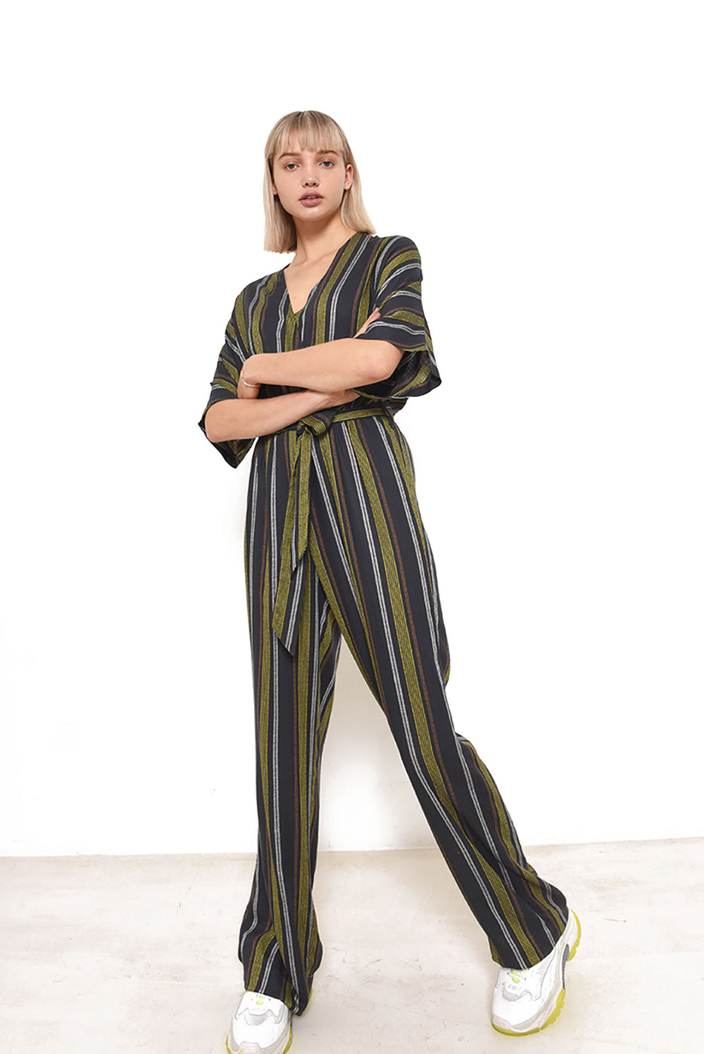 Woman wearing the Riva Jumpsuit sewing pattern from Fibre Mood on The Fold Line. A jumpsuit pattern made in viscose, crepe or viscose twill fabrics, featuring a V-neck wrap top, shaped 3/4 grown on sleeves, elasticised waist, self-fabric belt, wide trouse