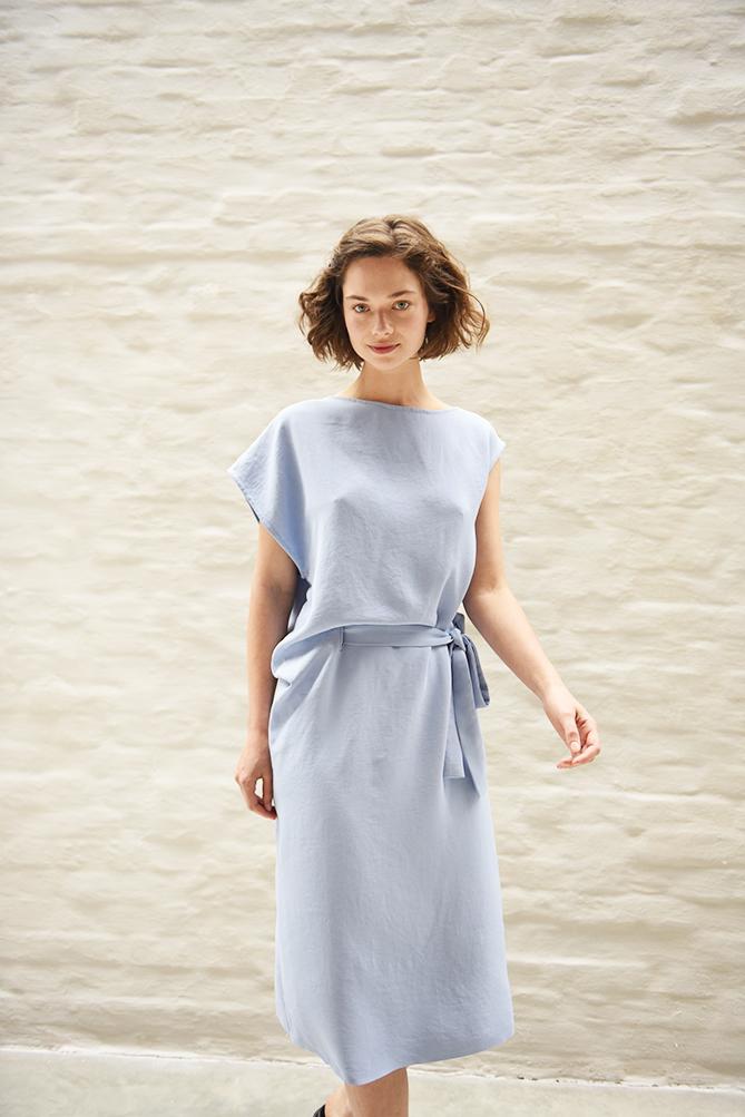 Woman wearing the Robyn Dress sewing pattern from Fibre Mood on The Fold Line. A dress pattern made in knitted or woven fabrics, featuring an asymmetric silhouette, below knee finish, boatneck, relaxed fit and self-tie belt.