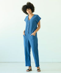 Woman wearing the Rory Jumpsuit sewing pattern from True Bias on The Fold Line. A jumpsuit pattern made in linen, chambray, silk noil or rayon challis fabrics featuring, a V-neck, angled patch pockets, front button closure, extended short sleeves and tape