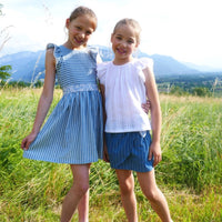 Children wearing the Child/Teen Rosea Top or Dress sewing pattern from Petits D'om on The Fold Line. A top and dress pattern made in poplin, batiste, viscose, Liberty, cotton veil or jersey fabrics, featuring a teardrop opening at the back, gathered shoul