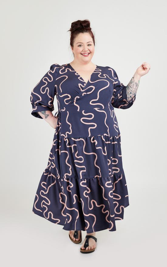 Woman wearing the Roseclair Dress sewing pattern from Cashmerette on The Fold Line. A maxi, wrap dress pattern made in linen, rayon, cotton, or double gauze fabrics, featuring a three tiered skirt, bishop sleeves with large angled cuffs and V-neck.