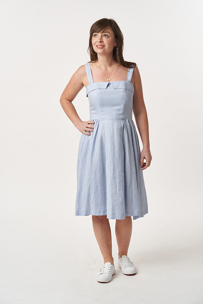 Woman wearing the Rosie Dress sewing pattern from Sew Over It on The Fold Line. A dress pattern made in cotton or linen fabric, featuring a 1950s-inspired silhouette, boned princess-seamed bodice, and full skirt with a box pleat at the front and gathers a