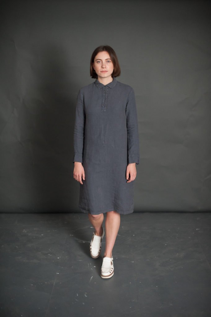 Woman wearing The Rugby Dress sewing pattern from Merchant & Mills on The Fold Line. A dress pattern made in light linens, fine wool, lightweight denim or silk fabrics featuring a semi-fit, rugby shirt style collar, cuffs and placket, full length sleeves 