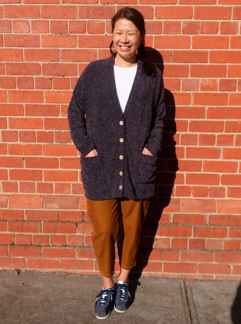 Woman wearing the Sabel Boyfriend Knit Cardi sewing pattern from Style Arc on The Fold Line. A cardigan pattern made in sweater knit fabrics, featuring an oversized fit, dropped shoulders, slim sleeves, large patch front pockets, large button front closur