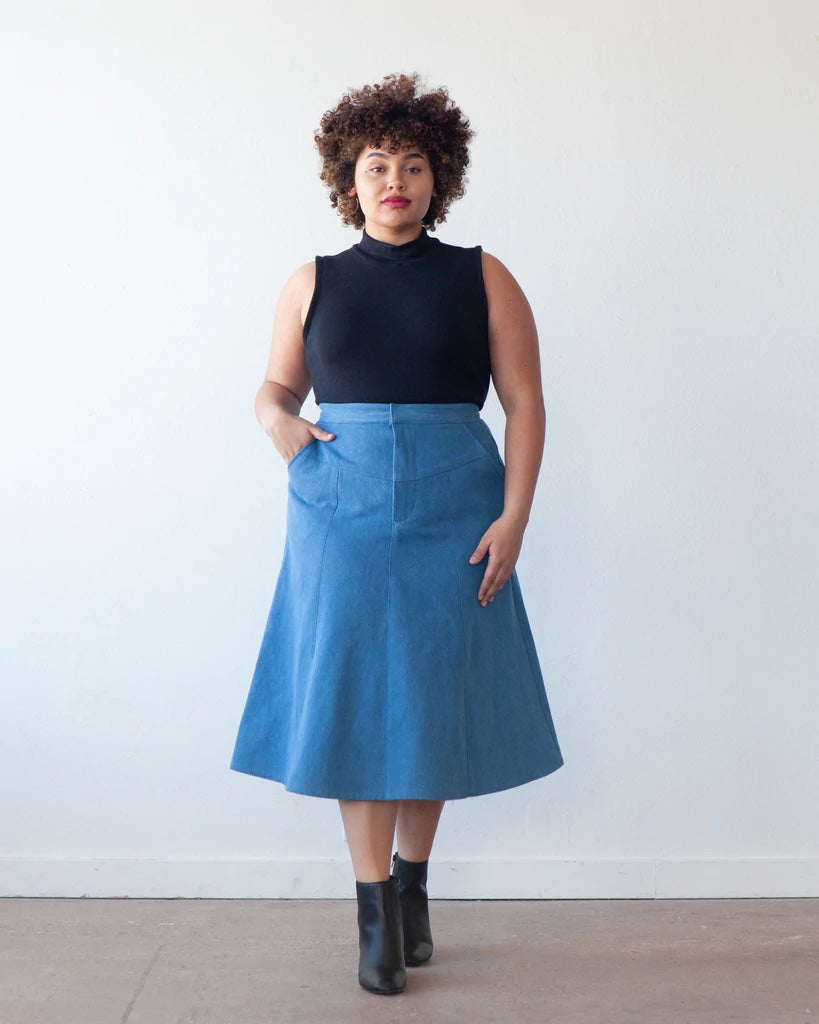 Woman wearing the Salida Skirt sewing pattern from True Bias on The Fold Line. A panelled skirt pattern made in denim, twill, corduroy, linen or chambray fabrics, featuring a front and back V-shaped yoke, high waist, front zipper fly, mid-calf length and 