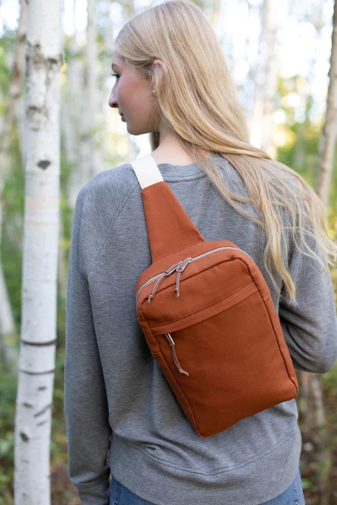 Woman wearing the Sandhill Sling Bag sewing pattern from Noodlehead on The Fold Line. A sling bag pattern made in canvas fabrics, featuring a front zippered pocket, interior pocket, outer zip closure and adjustable strap.
