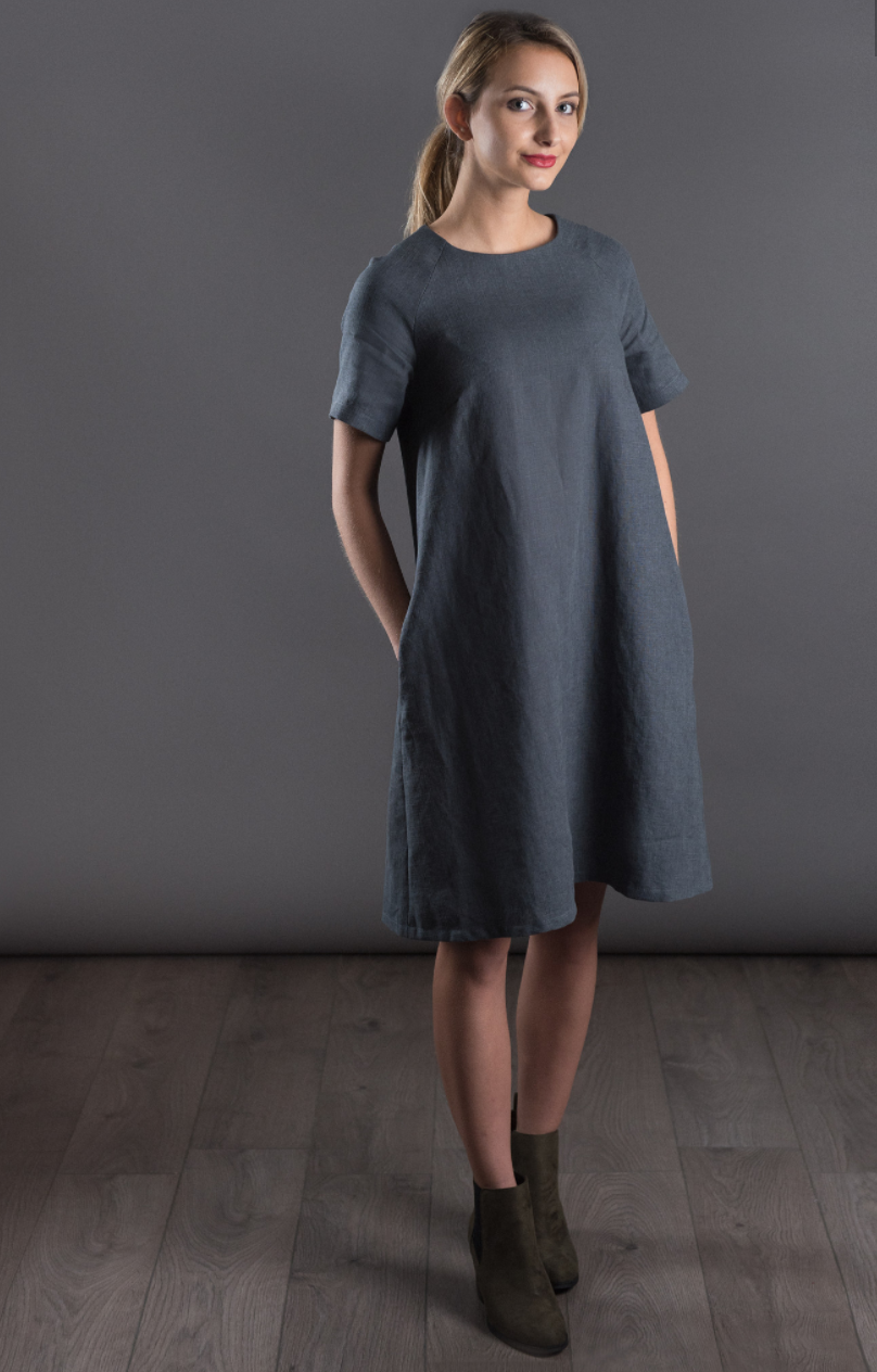 Woman wearing The Raglan Dress sewing pattern from The Avid Seamstress on The Fold Line. A dress pattern made in chambray, crepes, silk, viscose or cotton fabrics, featuring an A-line silhouette, short raglan sleeves, in-seam pockets, knee length hem, rou