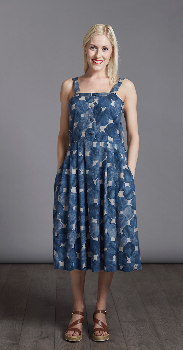 Woman wearing The Sun Dress sewing pattern from The Avid Seamstress on The Fold Line. A sun dress pattern made in cotton, chambray or linen fabrics, featuring a fitted bodice, square neckline, wide straps, button-down front, pleated skirt with pockets and