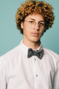 Man wearing the Ola Bow Tie sewing pattern from Melilot on The Fold Line. A bow tie pattern made in cotton, wool, silk or rayon fabrics, featuring a reversible style.