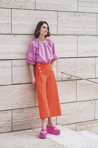 Woman wearing the Selah Trousers sewing pattern from Fibre Mood on The Fold Line. A trouser pattern made in denim, cotton twill, poplin, (fine) corduroy, or leather fabrics, featuring a sailor-style, high waist, wide legs, front button fastenings that tur