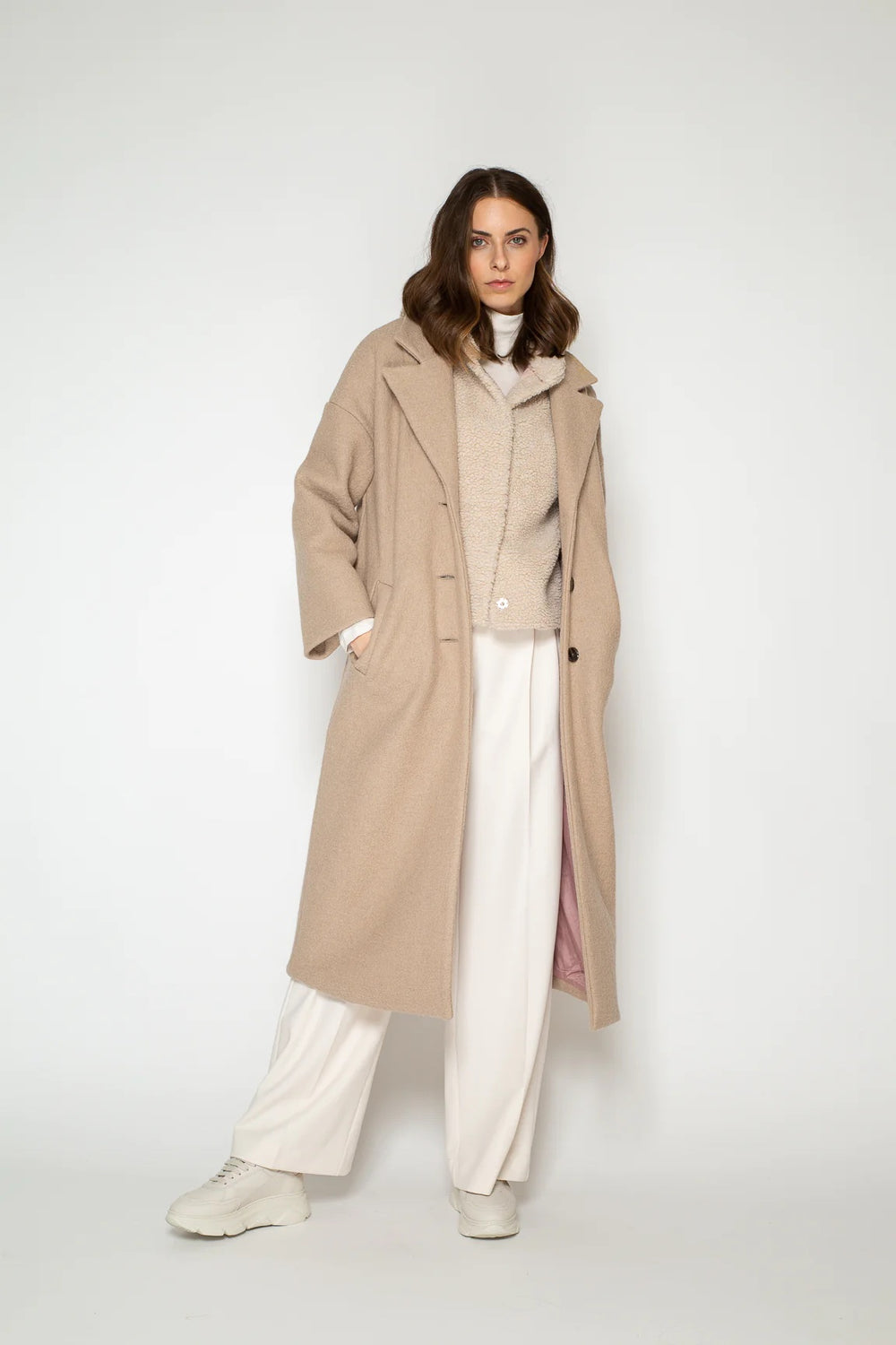Woman wearing the Selma Coat sewing pattern from Bara Studio on The Fold Line. A coat pattern made in wool, cotton or blended fibre fabrics, featuring a full lining, lapel collar, welt pockets, back vent, three button front closure, midi length and drop s