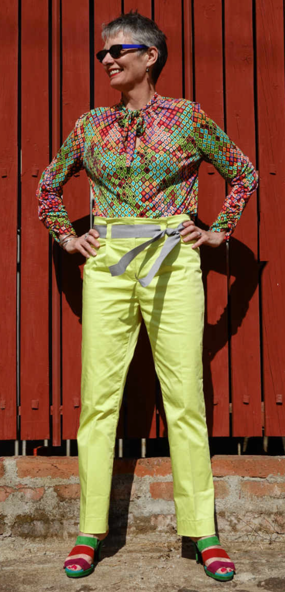 Woman wearing the Senorita Blouse sewing pattern by Alice and Co Patterns. A blouse pattern made in slinky silk jersey, bamboo, synthetic or viscose jersey or a fine wool knit fabric, featuring a front neck slit and bow tie and long sleeves that are ruche