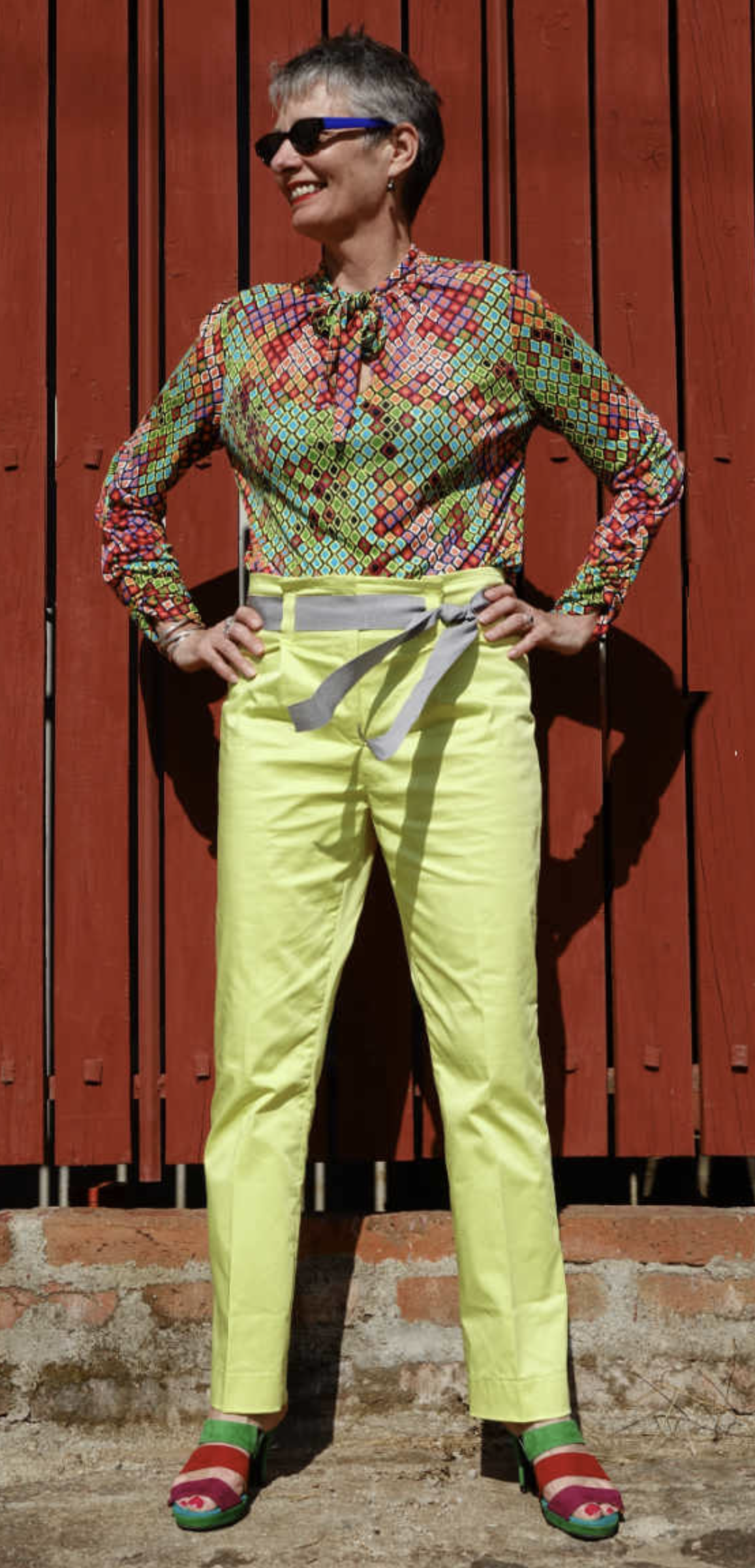 Woman wearing the Senorita Blouse sewing pattern by Alice and Co Patterns. A blouse pattern made in slinky silk jersey, bamboo, synthetic or viscose jersey or a fine wool knit fabric, featuring a front neck slit and bow tie and long sleeves that are ruche