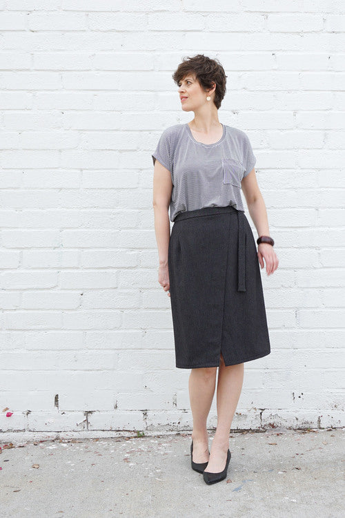 Woman wearing the Nita Wrap Skirt sewing pattern from Sew DIY on The Fold Line. A wrap skirt pattern made in cotton, linen, twill, poplin, sateen, wool crepe, corduroy or denim fabrics, featuring a fitted silhouette, angled front, knee length finish, wais