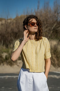 Woman wearing the Sienna Top sewing pattern from Fibre Mood on The Fold Line. A top pattern made in poplin, leather(ette), chambray, silk (satin), lyocell, crepe or double gauze fabrics, featuring a roomy cropped cut, back yoke with deep back pleat and ga