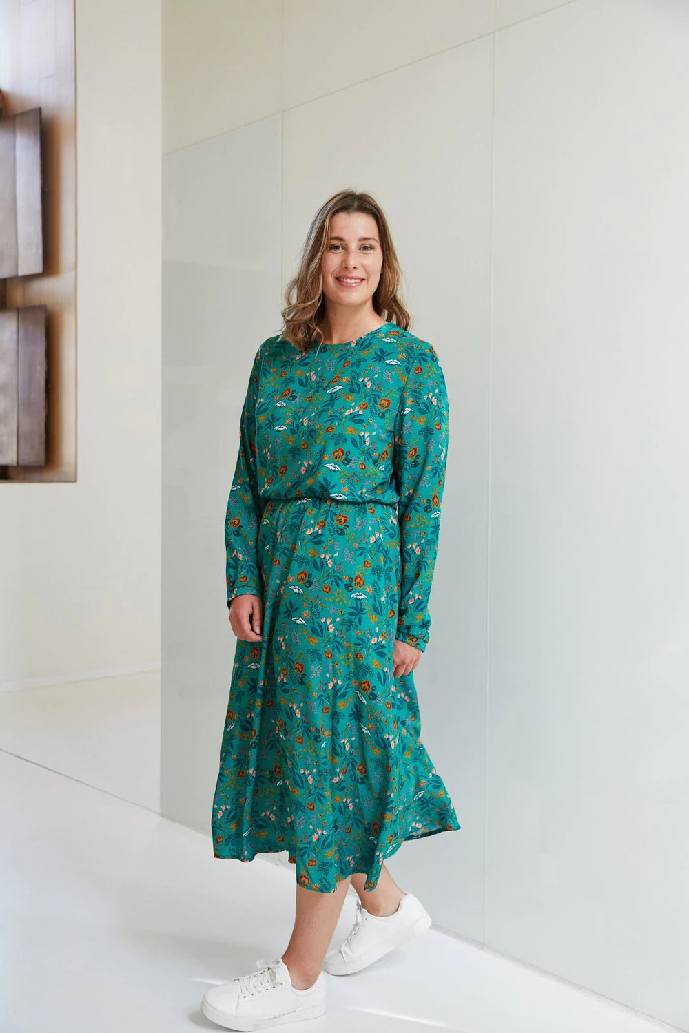 Woman wearing the Sienna Winter Dress sewing pattern from Atelier Jupe on The Fold Line. A dress pattern made in viscose or tencel fabrics, featuring a midi-length, loose-fitting bodice, long sleeves, 1/3 circle skirt, elasticated waist and round neckline