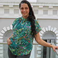 Woman wearing the Sille Shirt sewing pattern from Wardrobe by Me on The Fold Line. A top pattern made in cotton voile, viscose or silk fabrics, featuring front button closure, gathers at the neckline, curved hem, relaxed fit, dropped shoulders, deep armho