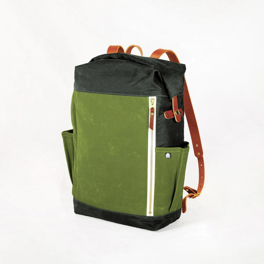 Photo showing the Slabtown Backpack sewing pattern from Klum House on The Fold Line. A rolltop backpack pattern made in canvas, waxed canvas, or denim fabrics, featuring a spacious main compartment, quick-access zipper, front zipper pocket, adjustable lea