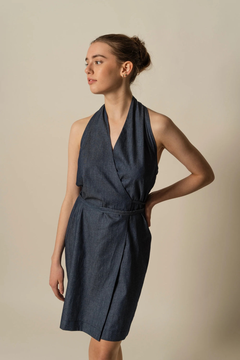 Woman wearing the Sophia Wrap Dress sewing pattern from Fieldwork Patterns on The Fold Line. A wrap dress pattern made in cottons, cotton mixes, linen, linen mixes or lightweight denim fabrics, featuring a tucked halter neckline, wrap around tie waist, ab