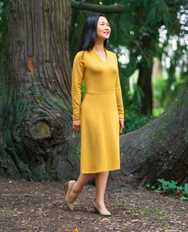 Woman wearing the Sovana Dress sewing pattern from Itch to Stitch on The Fold Line. A knit dress pattern made in French terry, double-brushed poly, cotton spandex jersey or poly spandex jersey fabrics, featuring long sleeves, fitted bodice, A-line midi sk