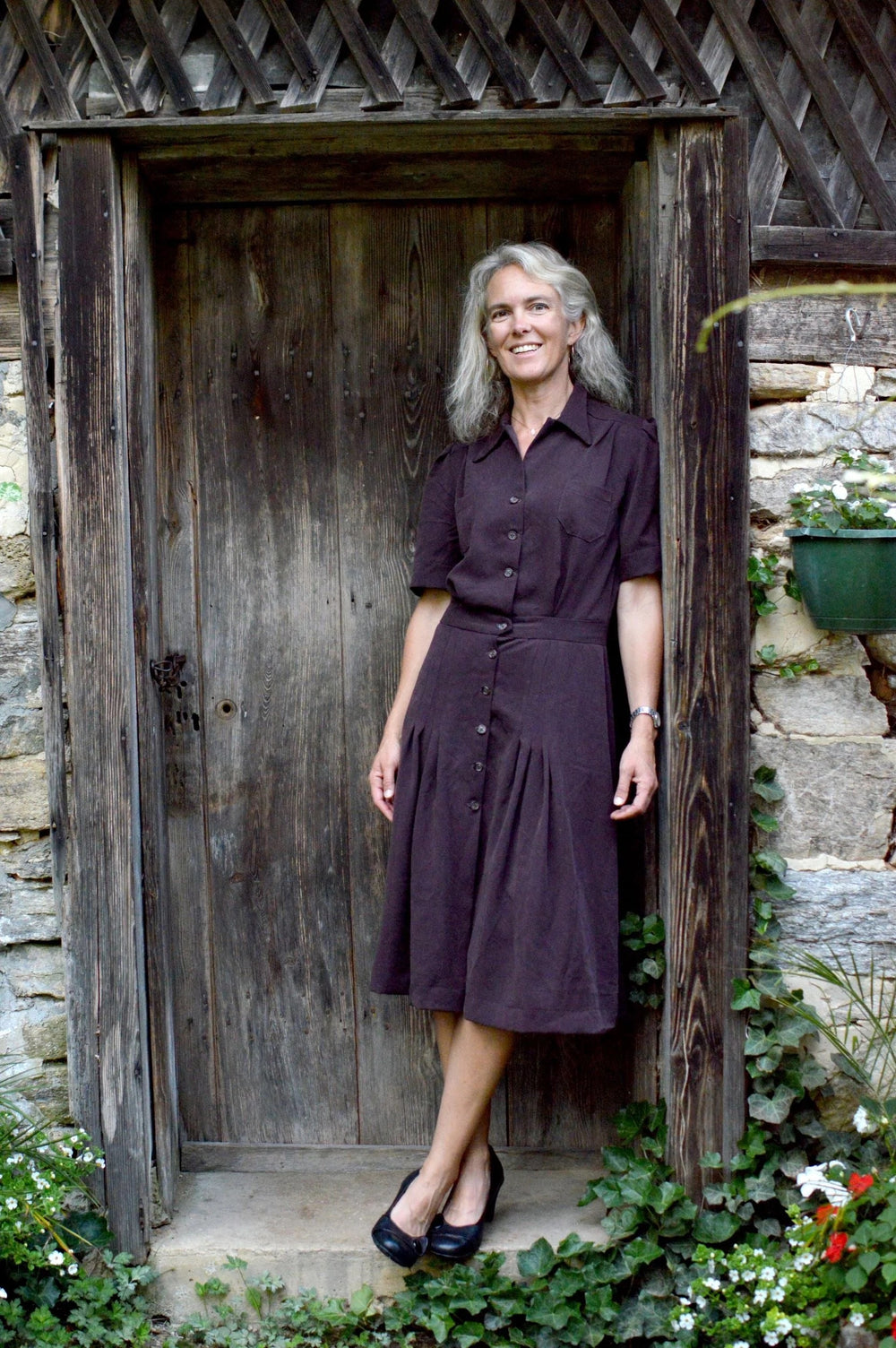 Woman wearing the 235 Sporty Forties Dress sewing pattern from Folkwear on The Fold Line. A shirtdress and knitted cardigan pattern made in linen, linen blends, cottons, cotton blends, rayon or silk fabrics, featuring a button front, breast patch pockets,