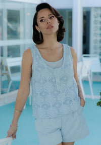 Woman wearing the Spritz Tank Top Duo sewing pattern from Maison Fauve on The Fold Line. A sleeveless top pattern made in fine jacquard, twill, crepe, poplin, voile, lace, cotton, viscose, or silk fabric, featuring two tank tops, one with a button placket