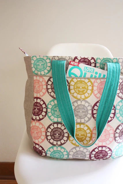 Photo showing the Super Tote sewing pattern from Noodlehead on The Fold Line. A tote bag pattern made in heavy linen, denim, canvas or twill fabrics, featuring a generous size, recessed zip closure, roomy interior pockets, front exterior pocket, piping an