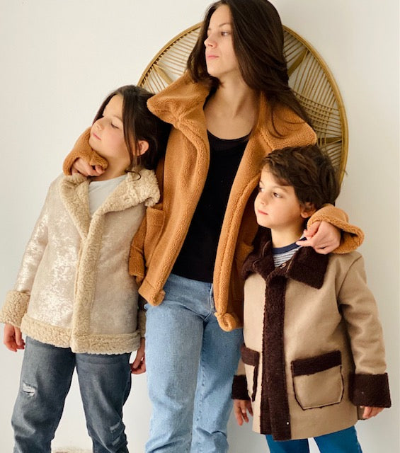 Children wearing the Mini Sweet Winter Biker Jacket sewing pattern from You Made My Day on The Fold Line. A jacket pattern made in double-sided faux leather/faux fur fabrics, featuring a collar, button front closure, front patch pockets, full length sleev