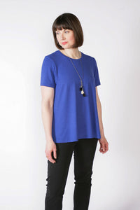 Woman wearing the Swing Tee sewing pattern from The Sewing Workshop on The Fold Line. A top pattern made in light to medium weight knit fabrics, featuring a high curved neckline, fitted shoulders, short sleeves, A-line swing shape, neck binding and topsti