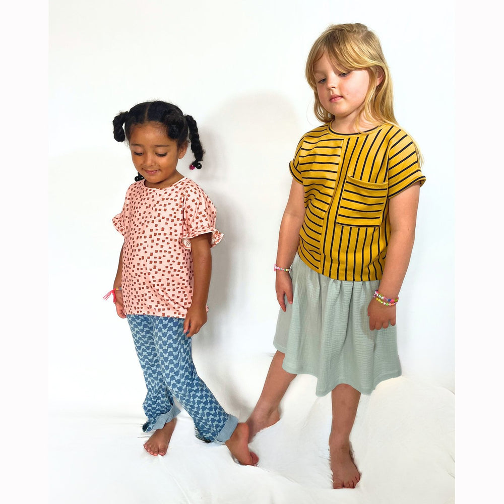 Children wearing the Baby/Child Sydney Tee sewing pattern from Pattern Paper Scissors on The Fold Line. A T-shirt pattern made in jersey, sweat, terry, stretch crepe, and knit fabrics, featuring a round neckline, patch pocket, crossover back and frilled s