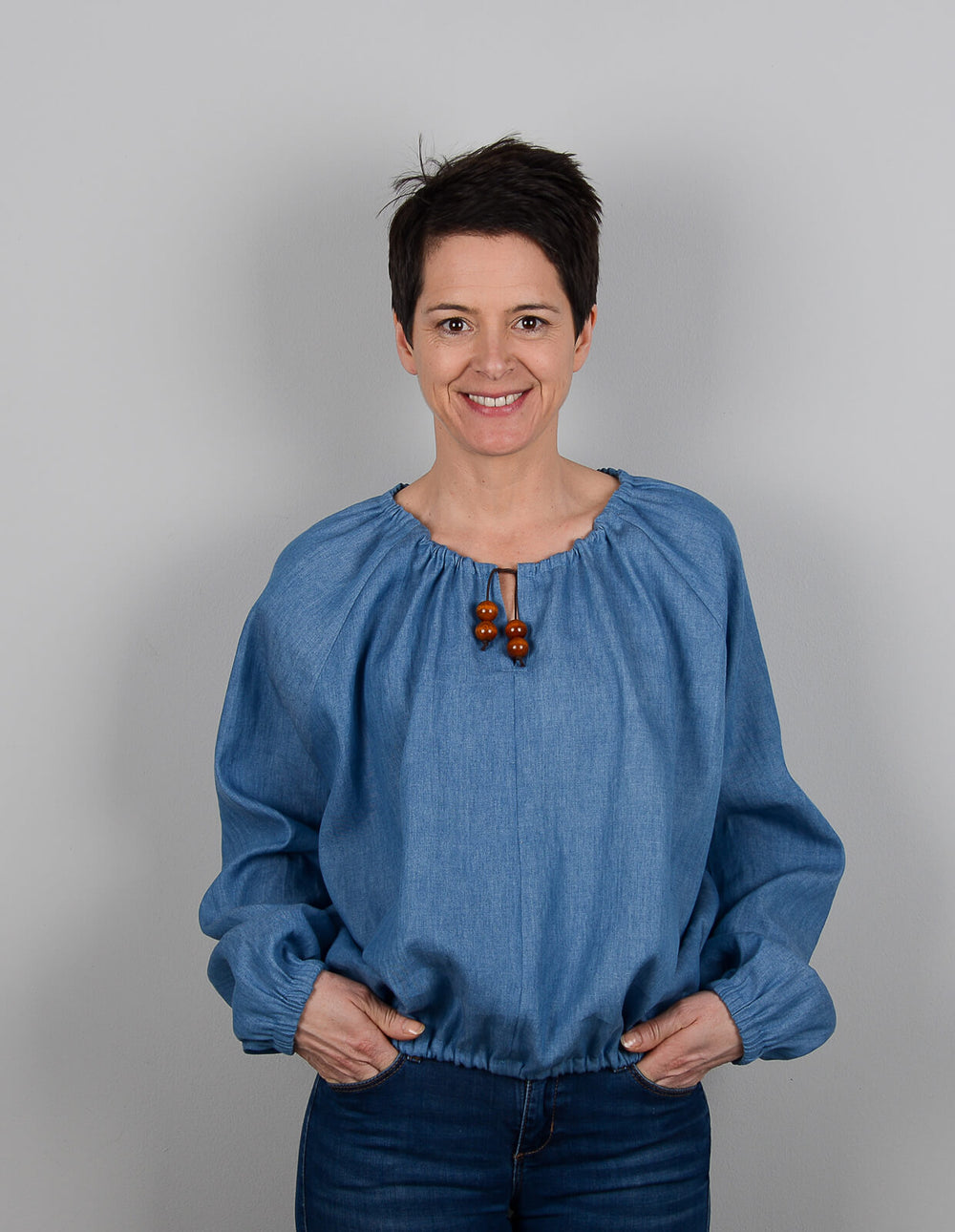 Woman wearing the Gathered-neck Top sewing pattern from The Maker's Atelier on The Fold Line. A top pattern made in light to medium weight cottons, chambrays, lightweight linens, fluid silks and viscose mixed fabrics, featuring a relaxed fit, raglan sleev
