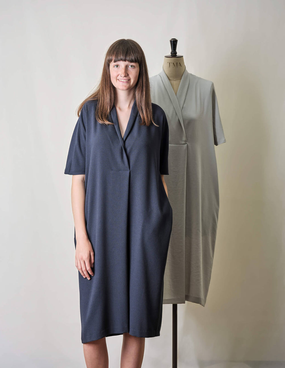 Woman wearing the Shawl Collar Dress sewing pattern from The Maker's Atelier on The Fold Line. A dress pattern made in wool, linen, cotton or viscose fabrics, featuring a relaxed fit, shawl collar, V-neck, folded pleat front detail, in-seam pockets, pull-