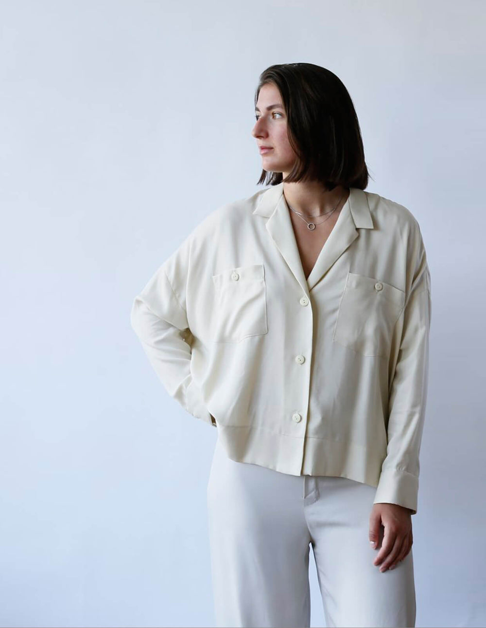Woman wearing the Lounge Shirt sewing pattern from The Maker's Atelier on The Fold Line. A shirt pattern made in tana Lawn, cotton, linen, viscose or tencel fabrics, featuring an oversized fit, full length sleeves with loose cuffs, collar, front button cl