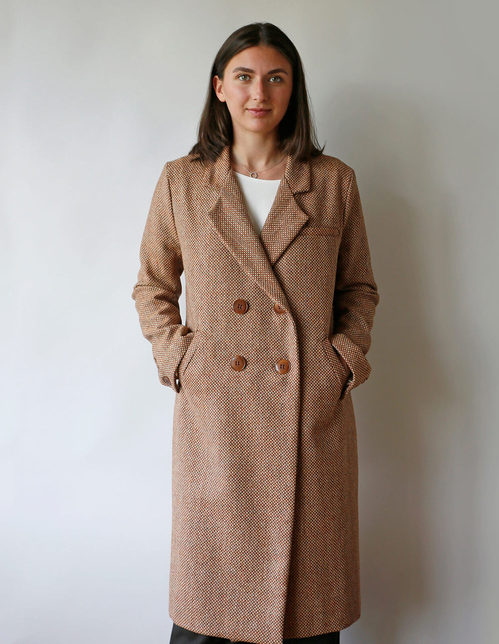Woman wearing the Classic Coat sewing pattern from The Maker's Atelier on The Fold Line. A double-breasted coat pattern made in medium weight coating fabrics, wools, tweeds, velvet, or corduroys fabrics, featuring a straight silhouette, set-in two-piece s