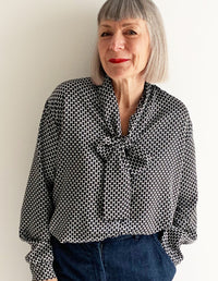 Woman wearing the Tie Front Blouse sewing pattern from The Maker's Atelier on The Fold Line. A blouse pattern made in silk, Tencel, viscose, fine cotton or Tana lawn fabrics, featuring cuffed sleeves with button closure, relaxed fit, pussy bow neck tie, f