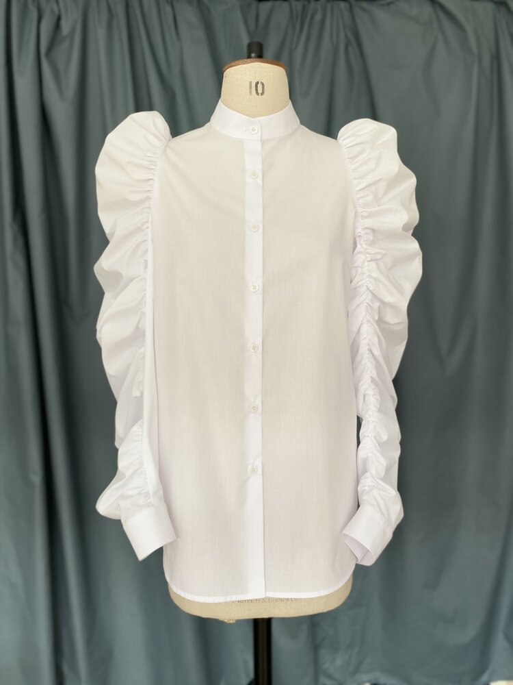 Mannequin wearing the TPCSH3 Angel Wing Shirt sewing pattern from Trend Patterns on The Fold Line. A shirt pattern made in cotton poplin fabrics, featuring a front placket, curved hem, shirt cuff, narrow stand collar and full gathered sleeve.