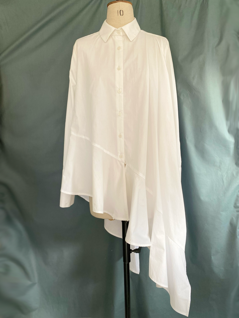 Mannequin wearing the TPCSH4 Ruffle Shirt sewing pattern from Trend Patterns on The Fold Line. A shirt pattern made in light to medium weight cotton fabrics, featuring an asymmetric trapeze silhouette, hem ruffle, front placket opening, back yoke, slim fi