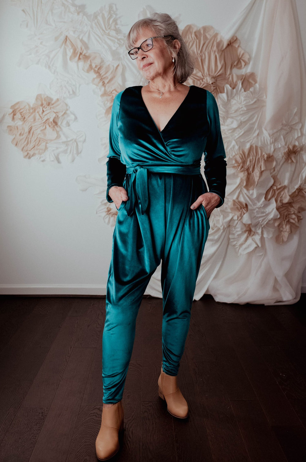 Woman wearing the Talam Jumpsuit sewing pattern from Sew Liberated on The Fold Line. A jumpsuit pattern made in bamboo, viscose, modal or jersey fabrics, featuring a crossover bodice, V-neck that secures with a wrap-around waist tie, long sleeves, pockets