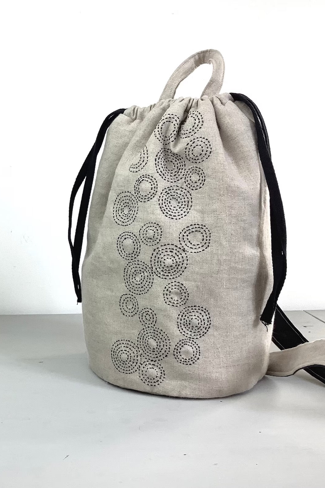 Photo showing the Taru Maru Crossbody Duffle Bag sewing pattern from Lasenby on The Fold Line. A duffle bag pattern made in canvas, linen, quilting cotton, twill, duck, denim, fine tweed, and Tana lawn fabrics, featuring a sashiko hand embroidery design, 