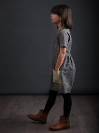 Child wearing Children's Gathered Dress sewing pattern from The Avid Seamstress on The Fold Line. A dress pattern made in light to medium weight fabrics, featuring grown-on short sleeves, patch pocket, round neckline, back waist gathers, knee length hem a