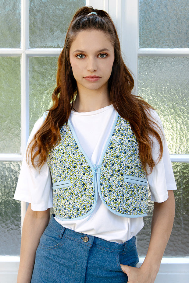 Woman wearing the Emily Vest sewing pattern from JULIANA MARTEJEVS on The Fold Line. A reversible quilted vest pattern made in cotton fabric, featuring a cropped length, bias binding around the edges, and double welt pockets.