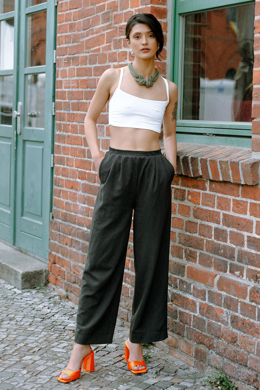 Woman wearing the Leslie Pants sewing pattern from JULIANA MARTEJEVS on The Fold Line. A trouser pattern made in light linen or denim, seersucker or thin virgin wool fabrics, featuring a slight cropped length, wide leg, side pockets, relaxed fit and elast