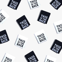Photo showing 'This Is the Back' Cotton Labels from Kylie & The Machine on The Fold Line. A washable, durable, and non-scratchy cotton label featuring a white or black background with white or black coloured text, they are all ready to be sewn into your h