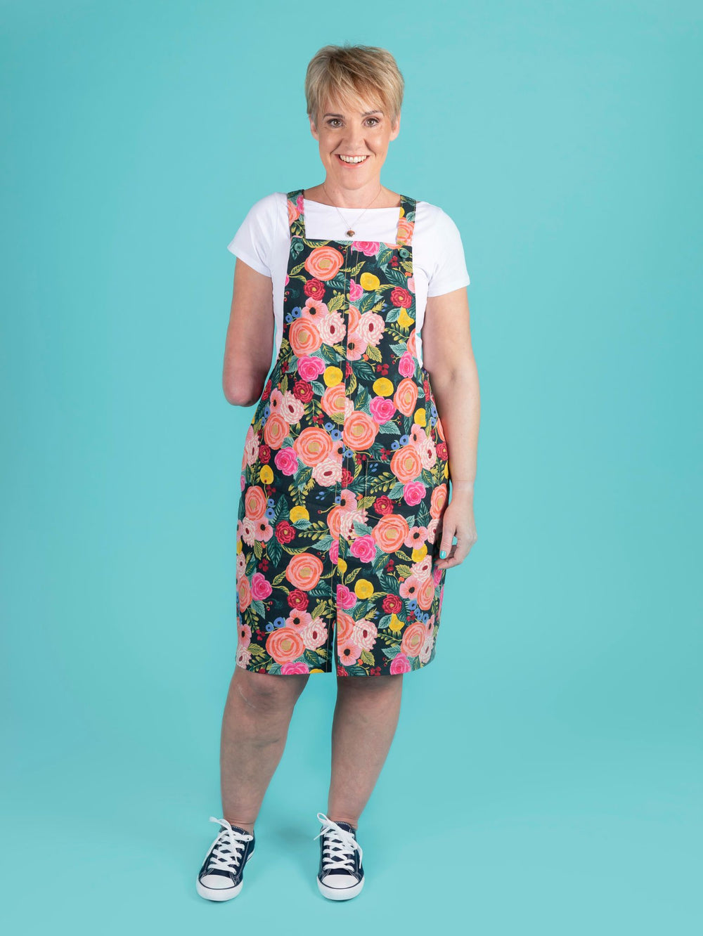 Woman wearing the Cleo Pinafore sewing pattern from Tilly and the Buttons on The Fold Line. A pinafore dress pattern made in soft linen, viscose, light denim or crepe fabrics featuring straps with button closure, knee-length hem with front split and front
