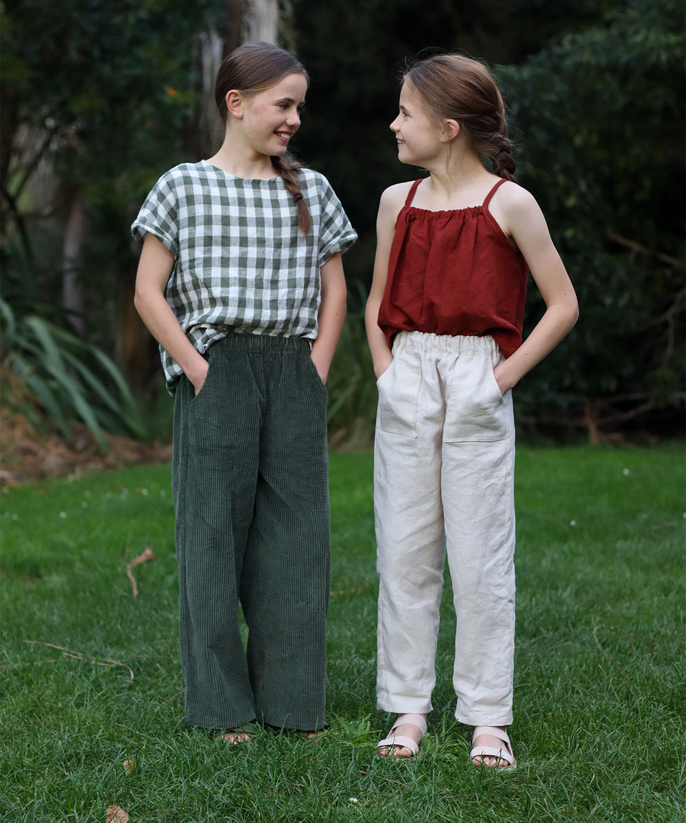 Children wearing the Tio Trousers sewing pattern from Below the Kōwhai on The Fold Line. A trouser pattern made in cotton, poly cotton, linen, chambray or corduroy fabrics featuring a relaxed fit, full length leg, front and back pockets, elastic waist, ta
