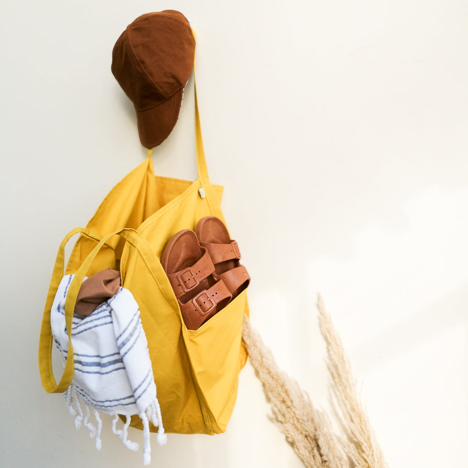 Photo showing the Tobi Tote sewing pattern from WISJ Designs on The Fold Line. A bag pattern made in canvas, sturdy cotton, corduroy, teddy, or oilskin fabrics, featuring a lined side pocket, reversible, and shoulder straps.