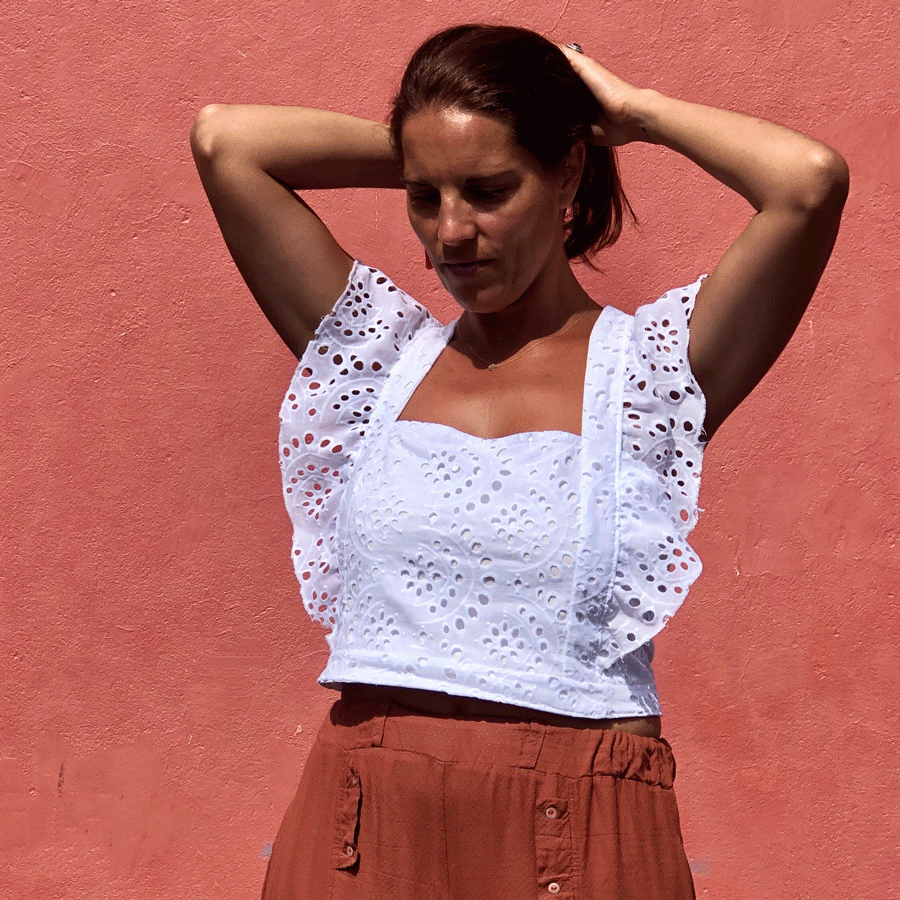 Woman wearing the Top 19 sewing pattern from You Made My Day Patterns on The Fold Line. A top pattern made in viscose, rayon, broderie anglaise, cupro, cotton or linen fabrics, featuring a cropped length, shoulder ruffles, square neckline, sleeveless, cro