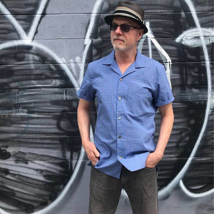 Man wearing the Men's Tropical Shirt sewing pattern from Wardrobe by Me on The Fold Line. A skirt pattern made in cotton, linen or silk fabrics, featuring front button closure, short-sleeves, convertible collar, side slits, double yoke, two back pleats an